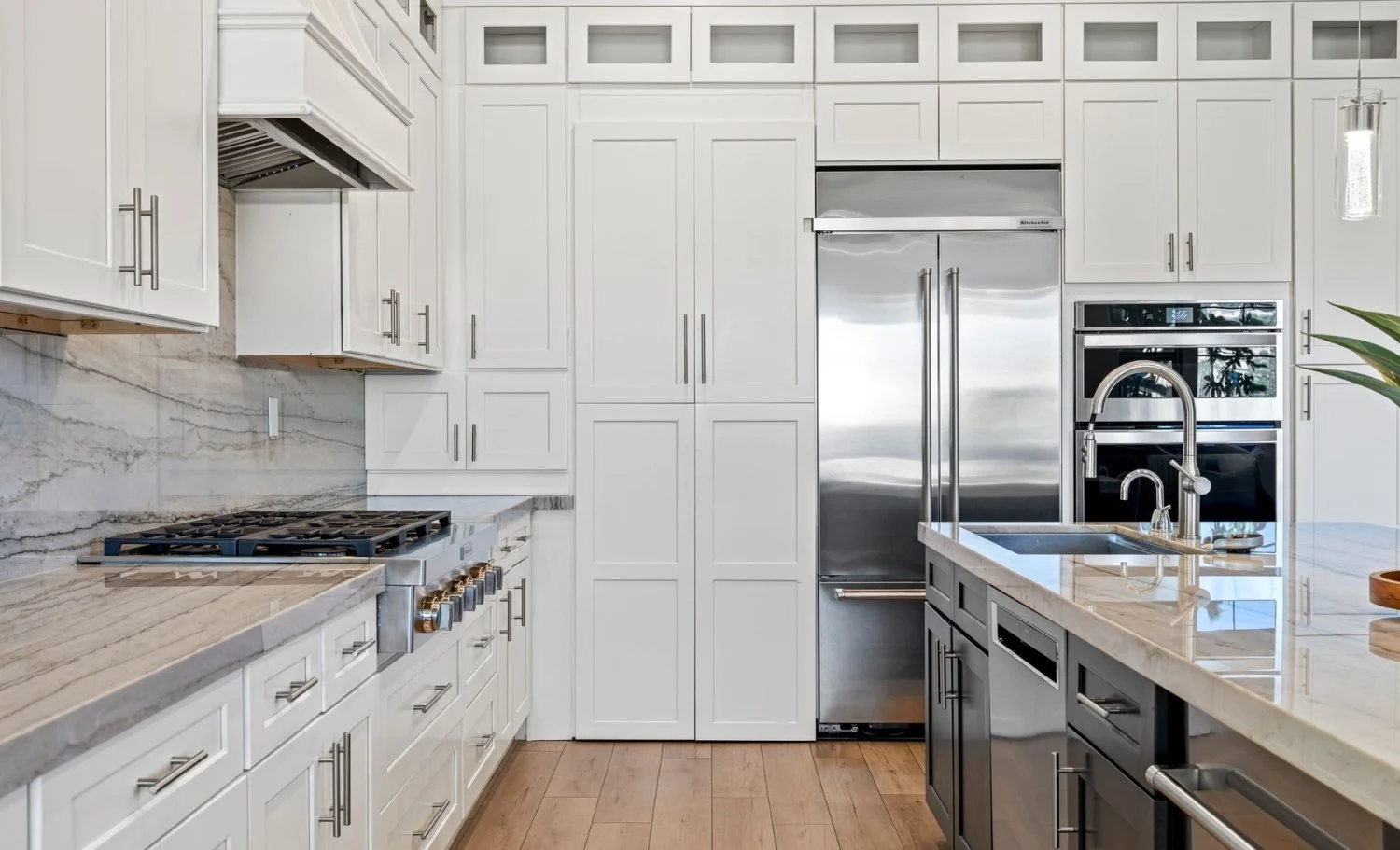 Modern gourmet kitchen with white shaker cabinets, marble countertops, stainless steel appliances, large center island, and gas range in a luxury California home.