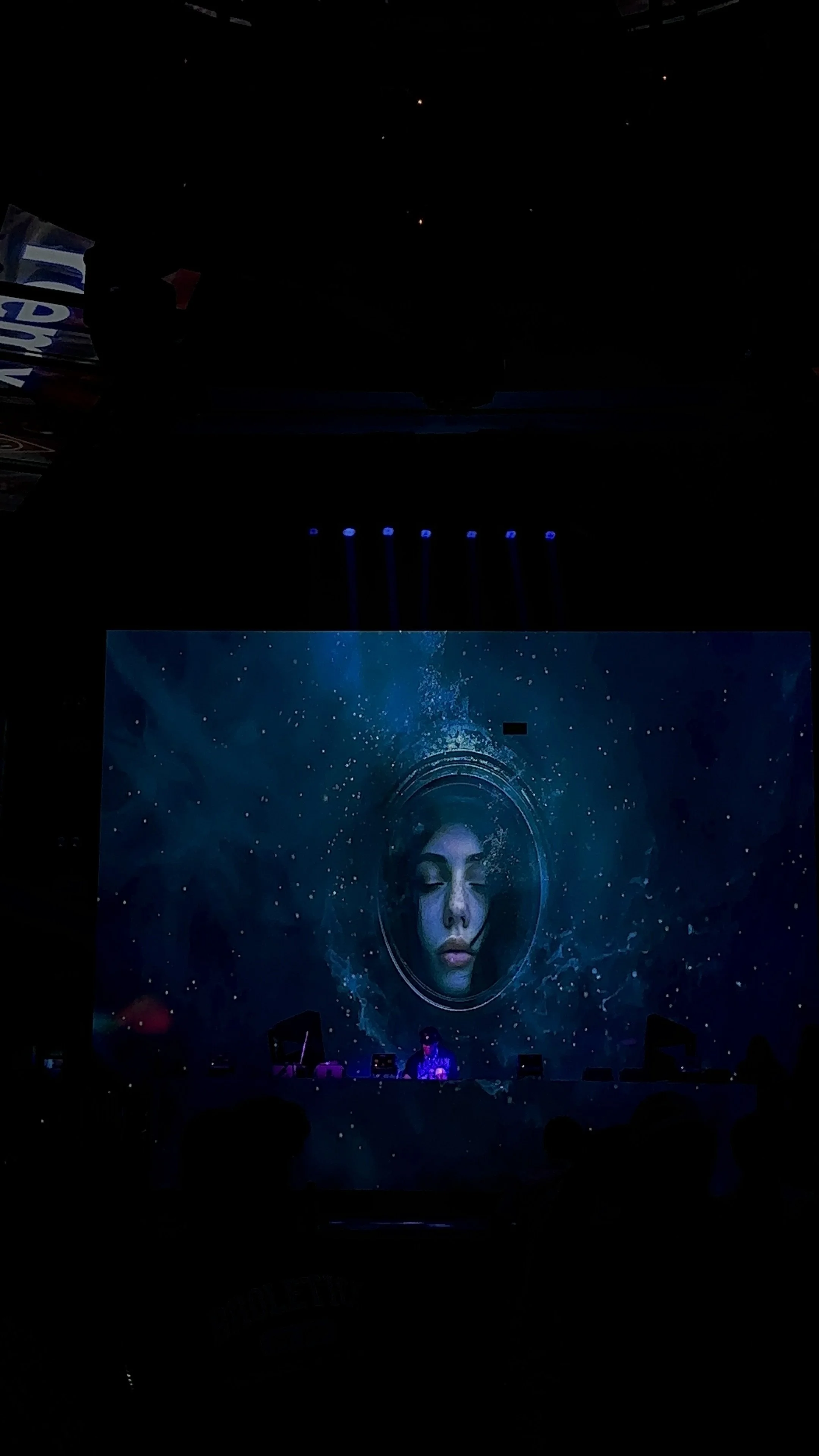 MADX Serenity surreal digital artwork displayed on large venue screen at Art Basel Miami, ethereal female face in cosmic blue tones glowing in darkened event space.