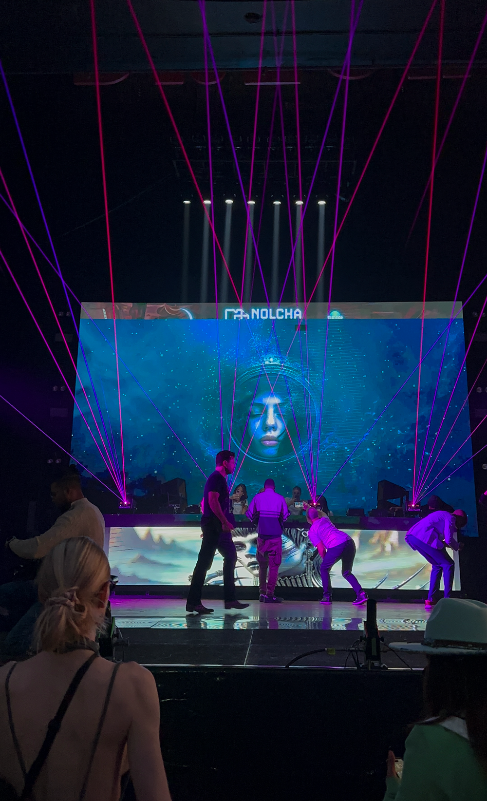 MADX Serenity animated digital artwork projected on large LED screen at Nolcha Shows Art Basel Miami with pink laser light show and live performers on stage below.