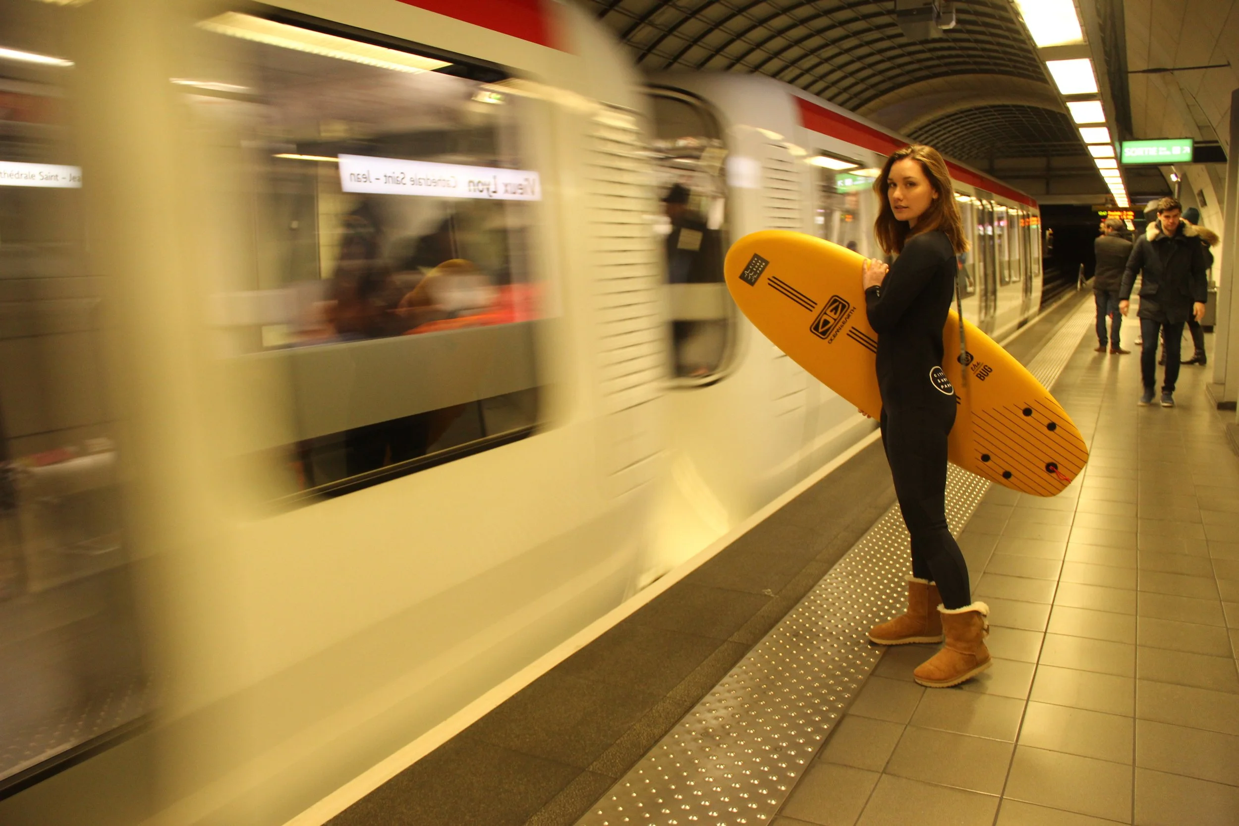Surfeuse avec sa planche attend le métro à Lyon pour aller surfer chez citysurfpark la vague indoor de 'lol vallée