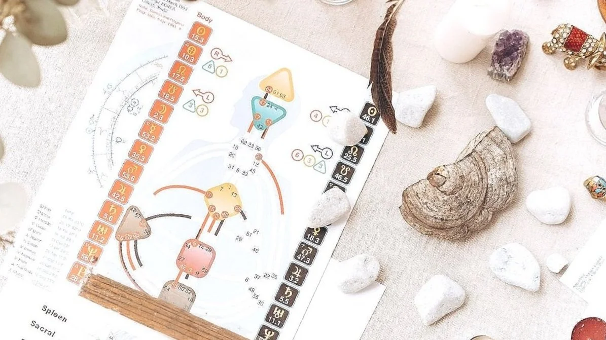 Human Design Reading. Quantum Human Design Reading. A diagram of a human body with various numbers and symbols, surrounded by stones, crystals, and jewelry on a table.