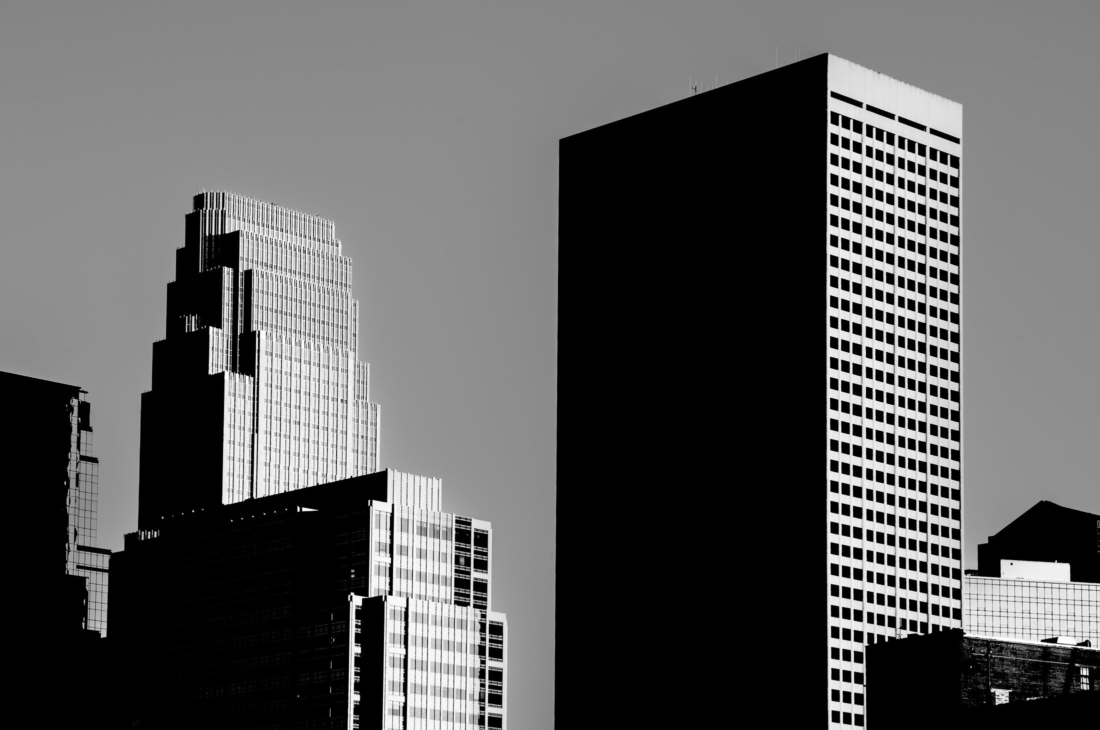 Black and white photo of tall skyscrapers within Minneapolis skyline, with a clear sky in the background.