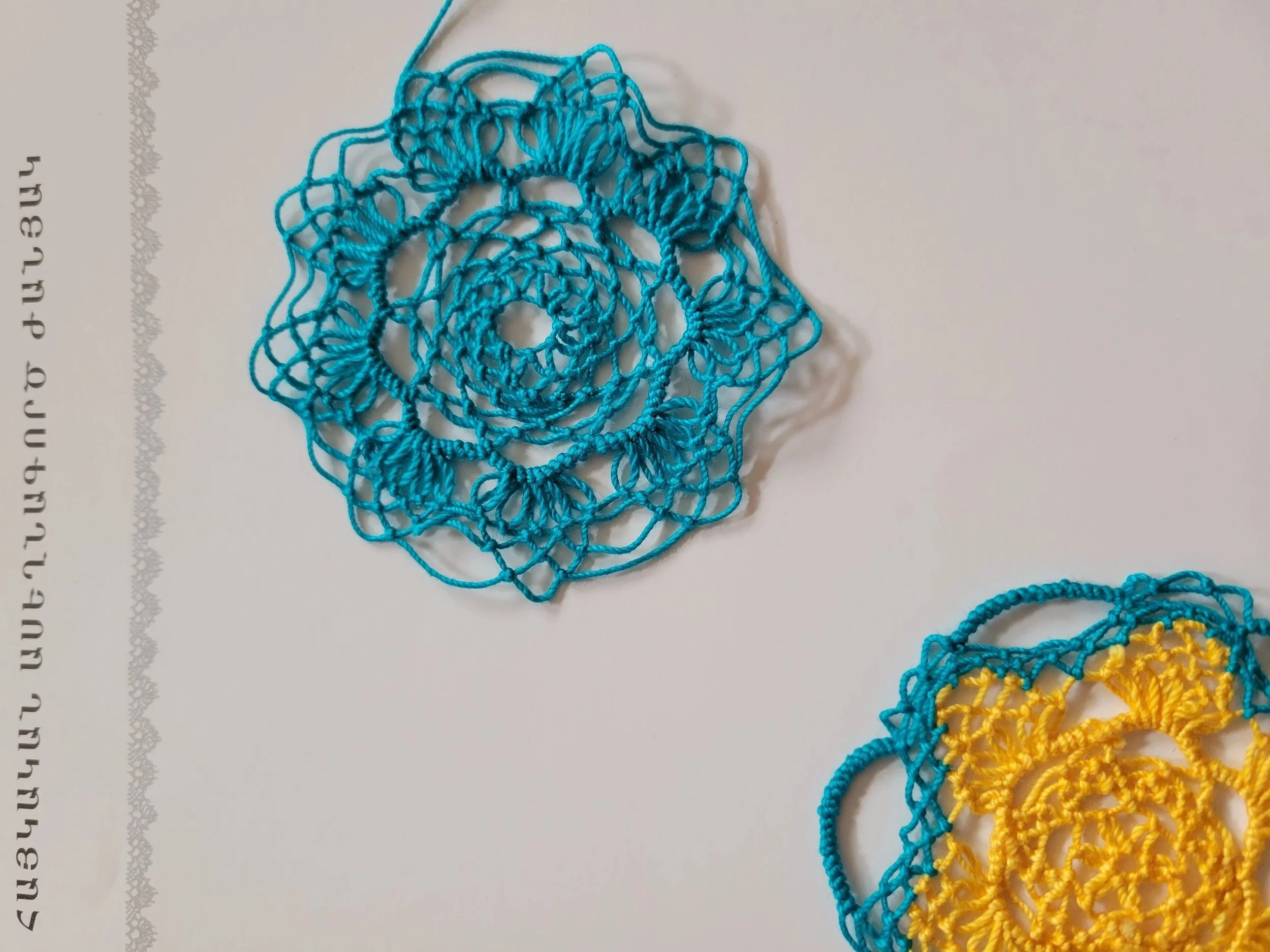 Ali Cat, small practice doilies paired with a page from Lusine Mkhitaryan's instructional text,    Հայկական Ասեղնագործ Ժանյակ (Armenian Needle Lace)   , cotton thread, Portland, Oregon, 2024. Photo credit: © Ali Cat 2024.