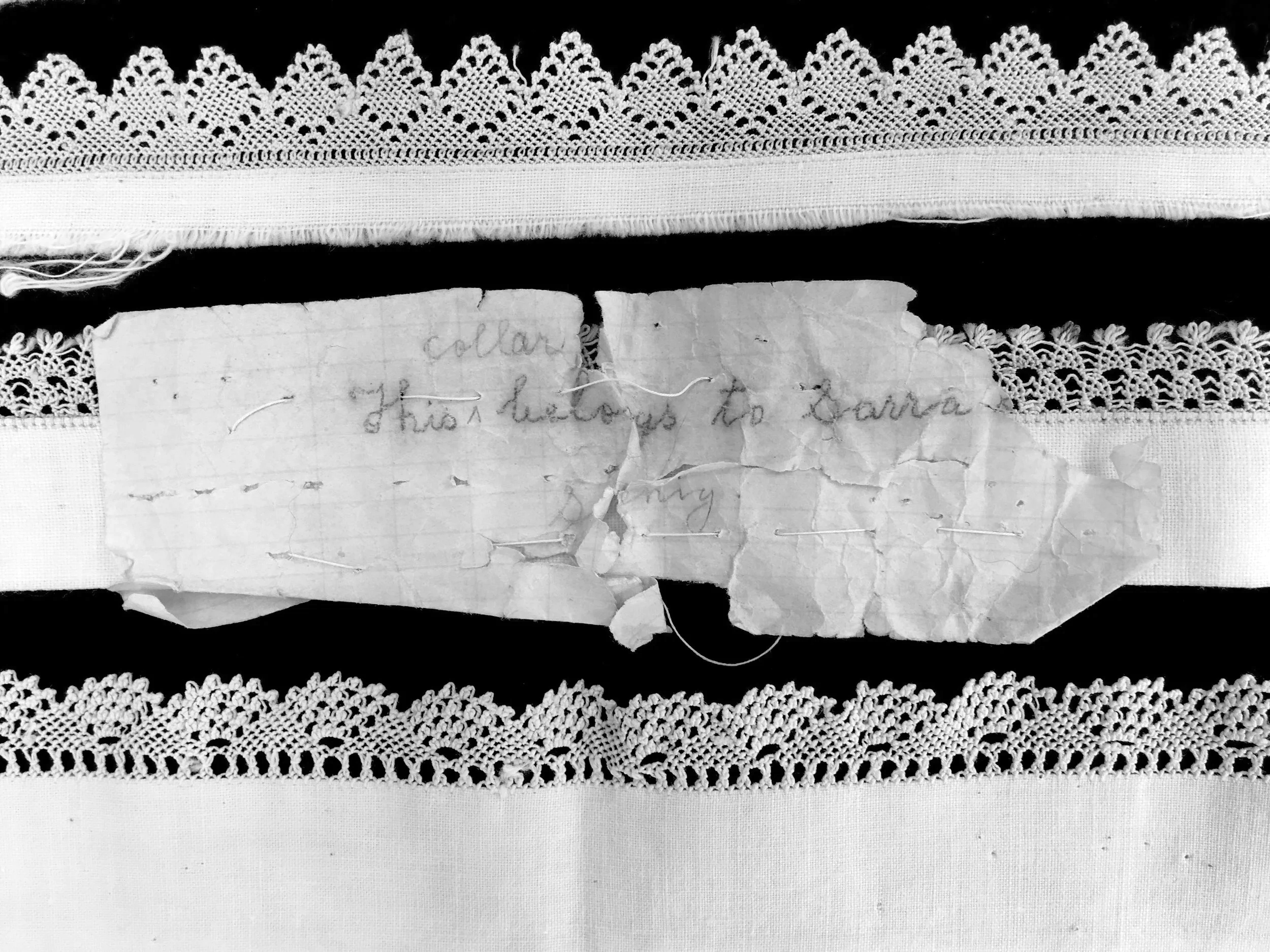 Black and white photo of four collars with Armenian needlelace trim and handwritten note stitched in
