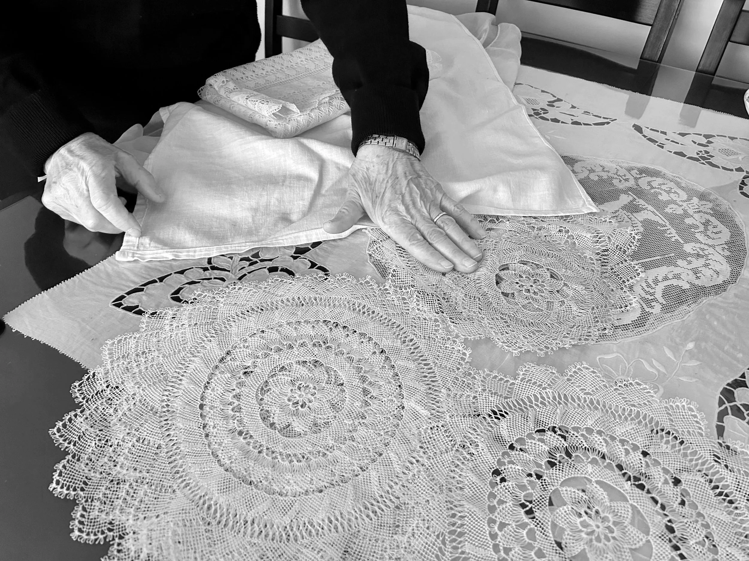 Black and white photo of Armenian needlelace doilies and their makers hands