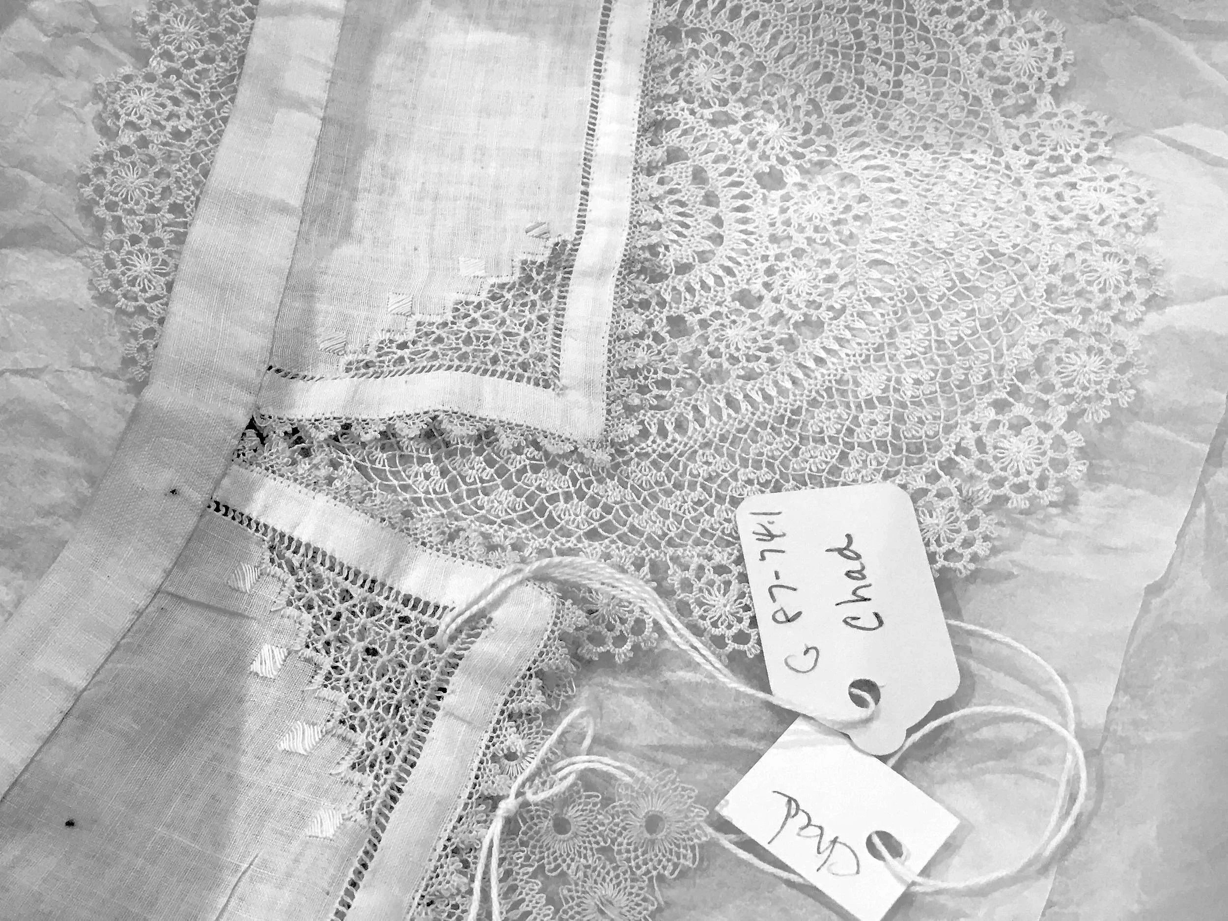 Black and white photo of Armenian needlework, including needlelace doily and trimmed collar, with museum tags