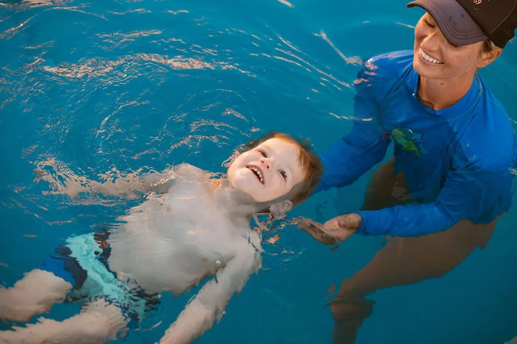 Instructor guiding young child in self-rescue swim lesson in pool