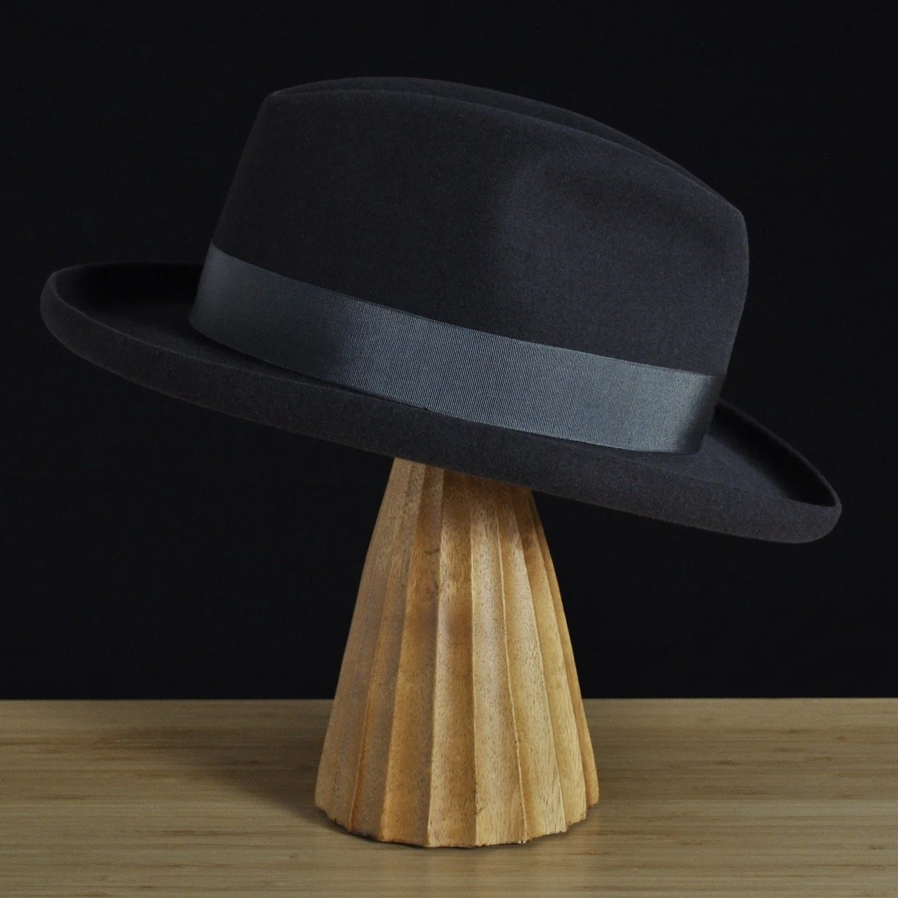 Vista lateral derecha del sombrero de fieltro antracita «The Westminster», con Copa estructurada, Ala rizada y cinta de grosgrain a juego con un clásico lazo doble.