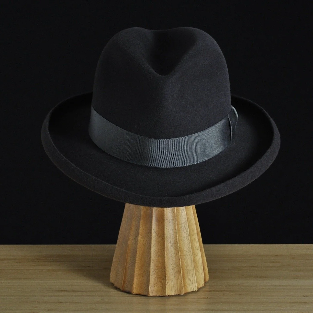 Vista frontal del sombrero de fieltro antracita «The Westminster», con copa estructurada, ala rizada y cinta de grosgrain a juego con un clásico lazo doble.