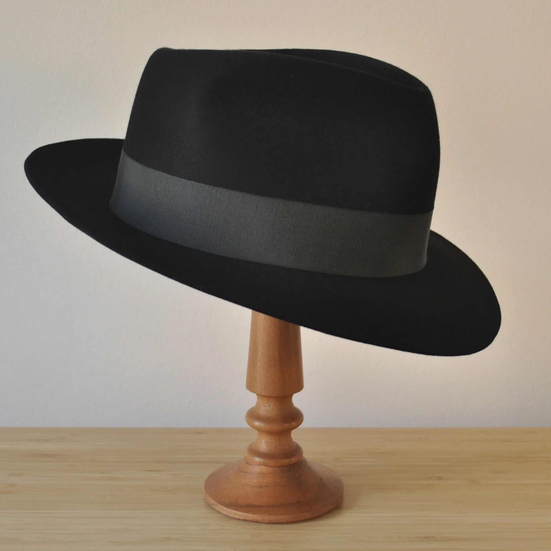 Three-quarter front right view of a black felt fedora with a clean structured crown, medium snap brim, and medium-dark bluish green grosgrain ribbon with classic bow.