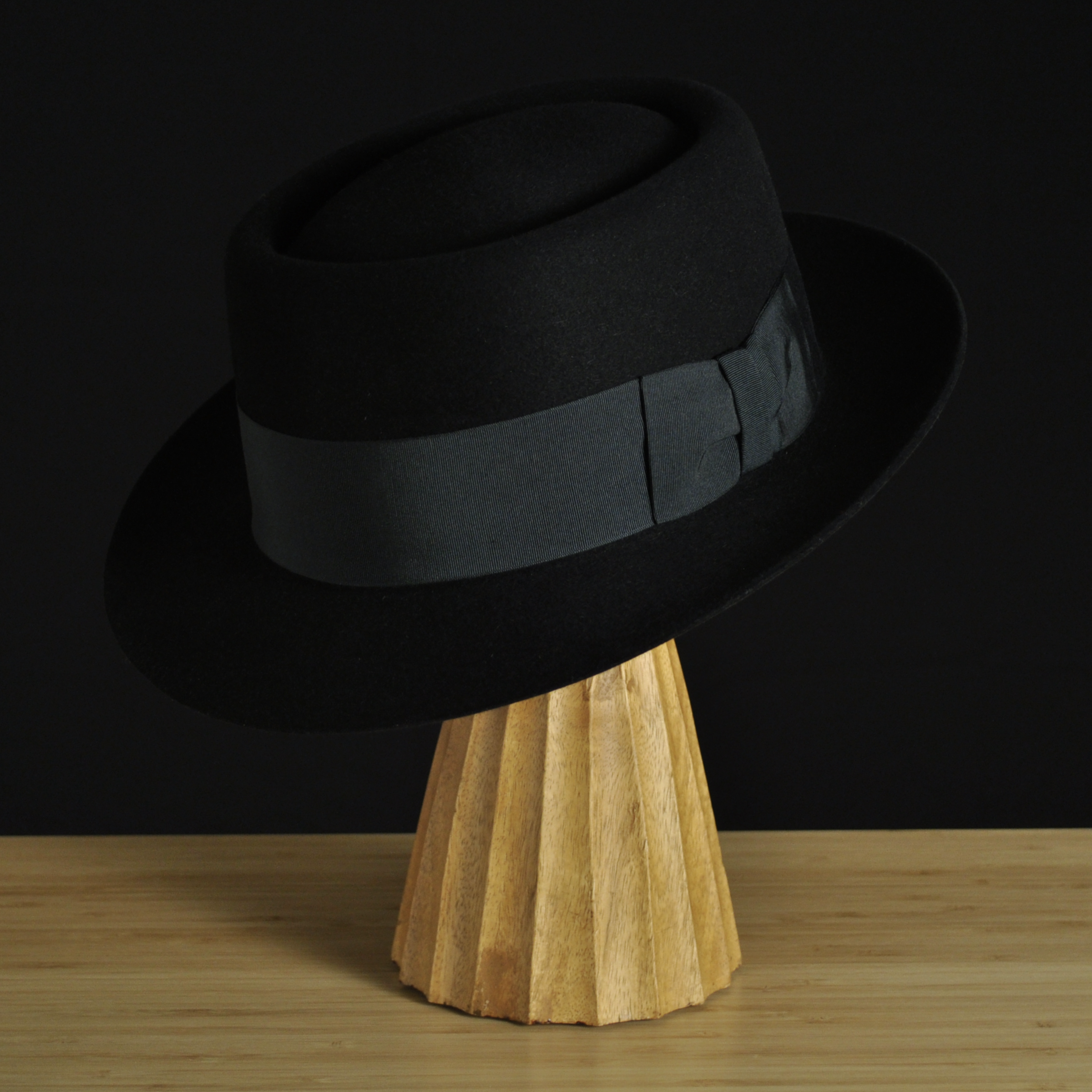 Three-quarter front left view of The Midtowner black felt fedora with a clean tapered crown, medium snap brim, and matching black grosgrain ribbon with classic bow.