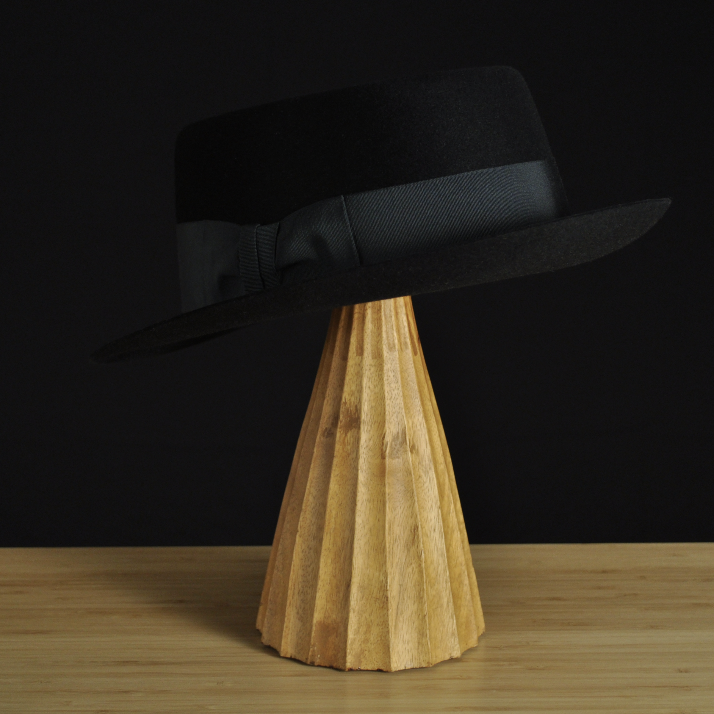 Three-quarter rear left view of The Midtowner black felt fedora with a clean tapered crown, medium snap brim, and matching black grosgrain ribbon with classic bow.