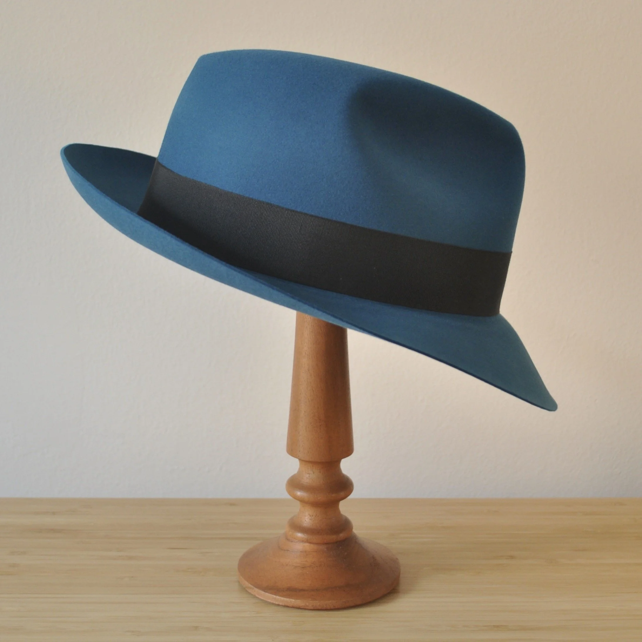 Right view of a cobalt blue felt fedora with a softly pinched centre dent crown, medium snap brim, and very dark blueish grey grosgrain ribbon with a modern tie (no bow).