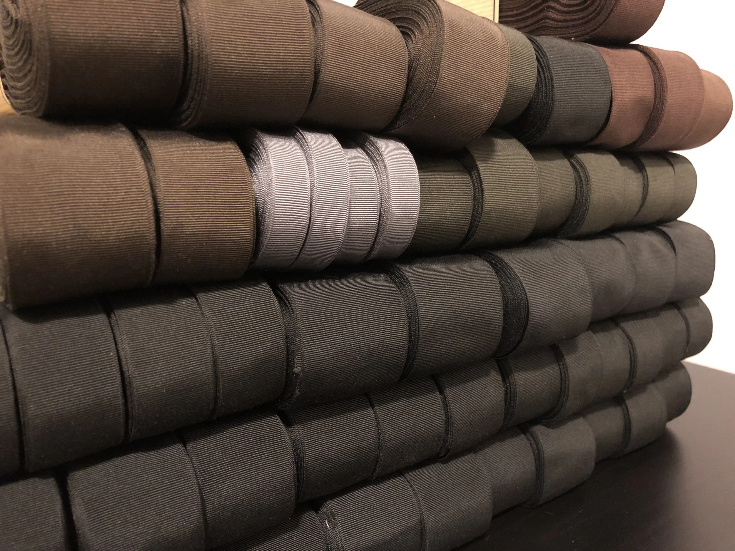 Multiple rolls of French vintage ribbon in various shades of blue, gray, and brown stacked horizontally.