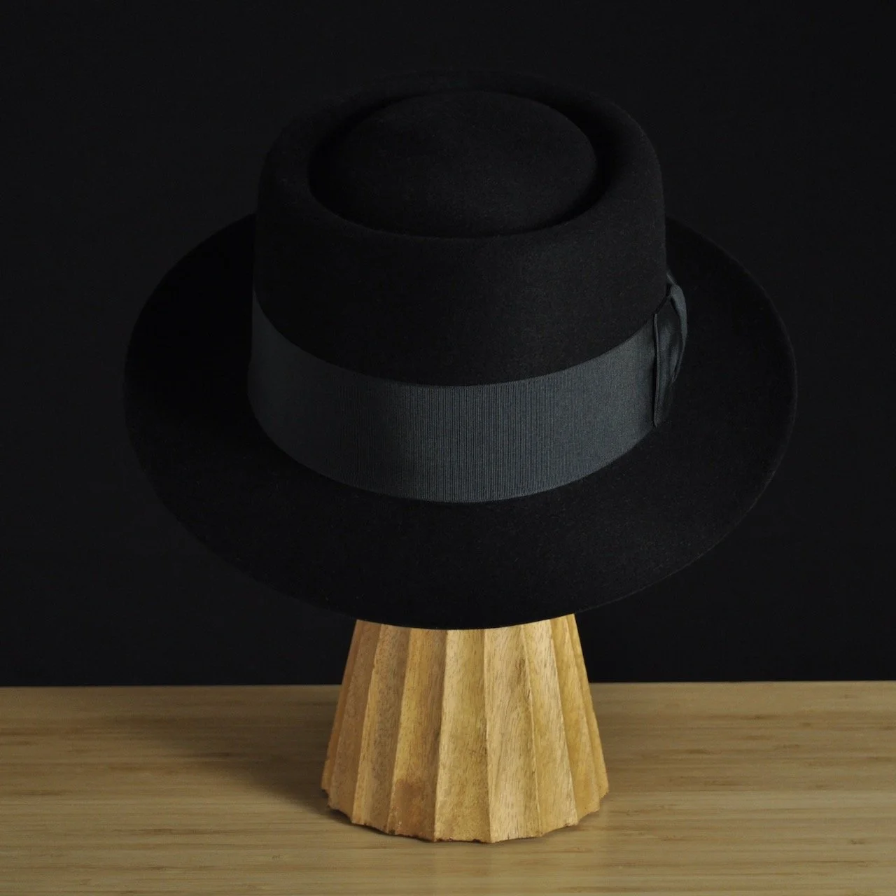 - Front view of The Midtowner black felt fedora with a clean tapered crown, medium snap brim, and matching black grosgrain ribbon with classic bow.