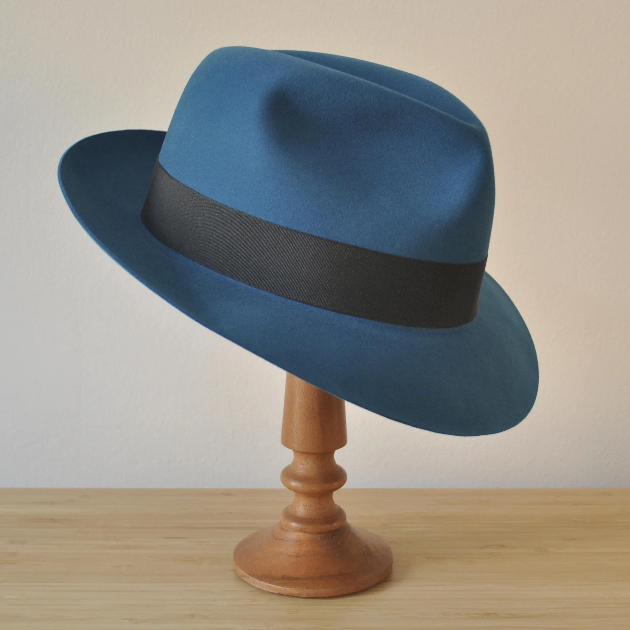 Three-quarter front right view of a cobalt blue felt fedora with a softly pinched centre dent crown, medium snap brim, and very dark blueish grey grosgrain ribbon with a modern tie (no bow).