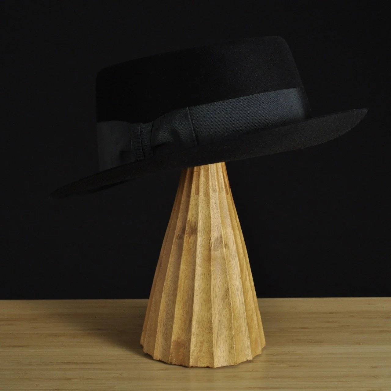 - Three-quarter rear left view of The Midtowner black felt fedora with a clean tapered crown, medium snap brim, and matching black grosgrain ribbon with classic bow.