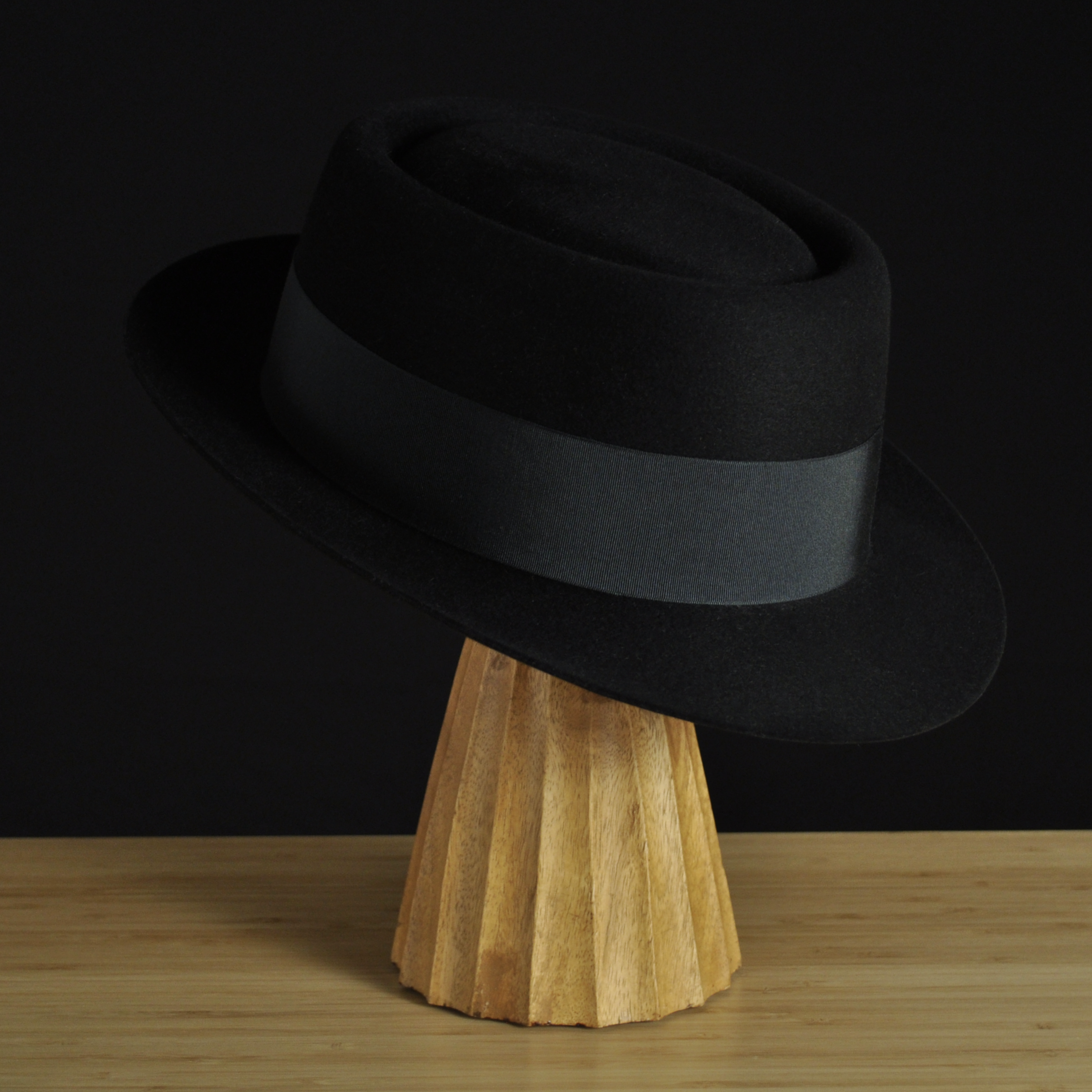 Three-quarter front right view of The Midtowner black felt fedora with a clean tapered crown, medium snap brim, and matching black grosgrain ribbon with classic bow.