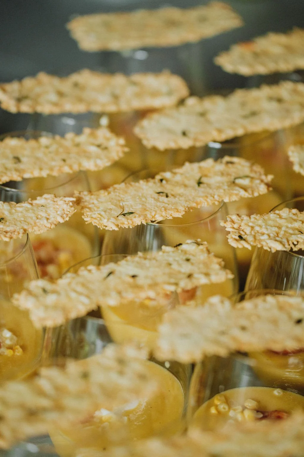 Close-up view of multiple dessert parfaits in glass cups topped with crispy oat crust.