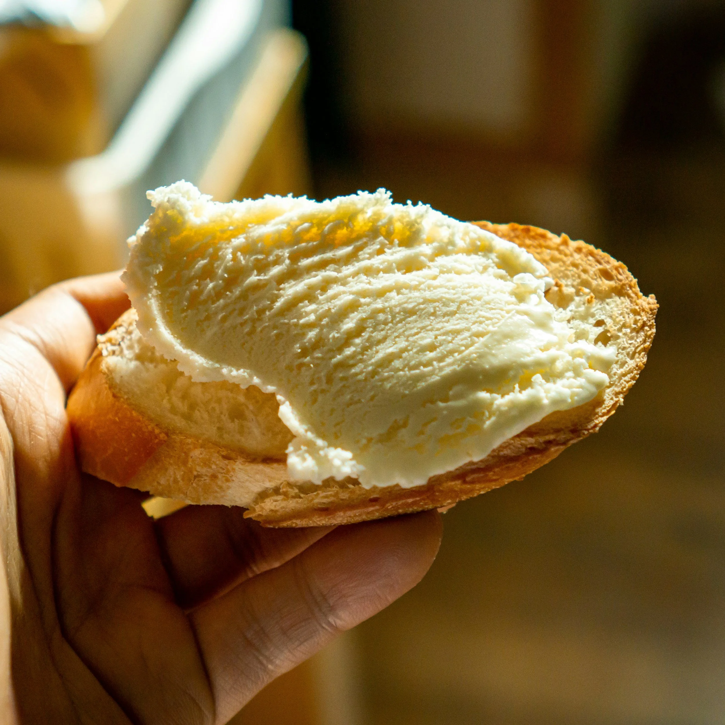 Thick smear of yellow gold butter on crusty bread