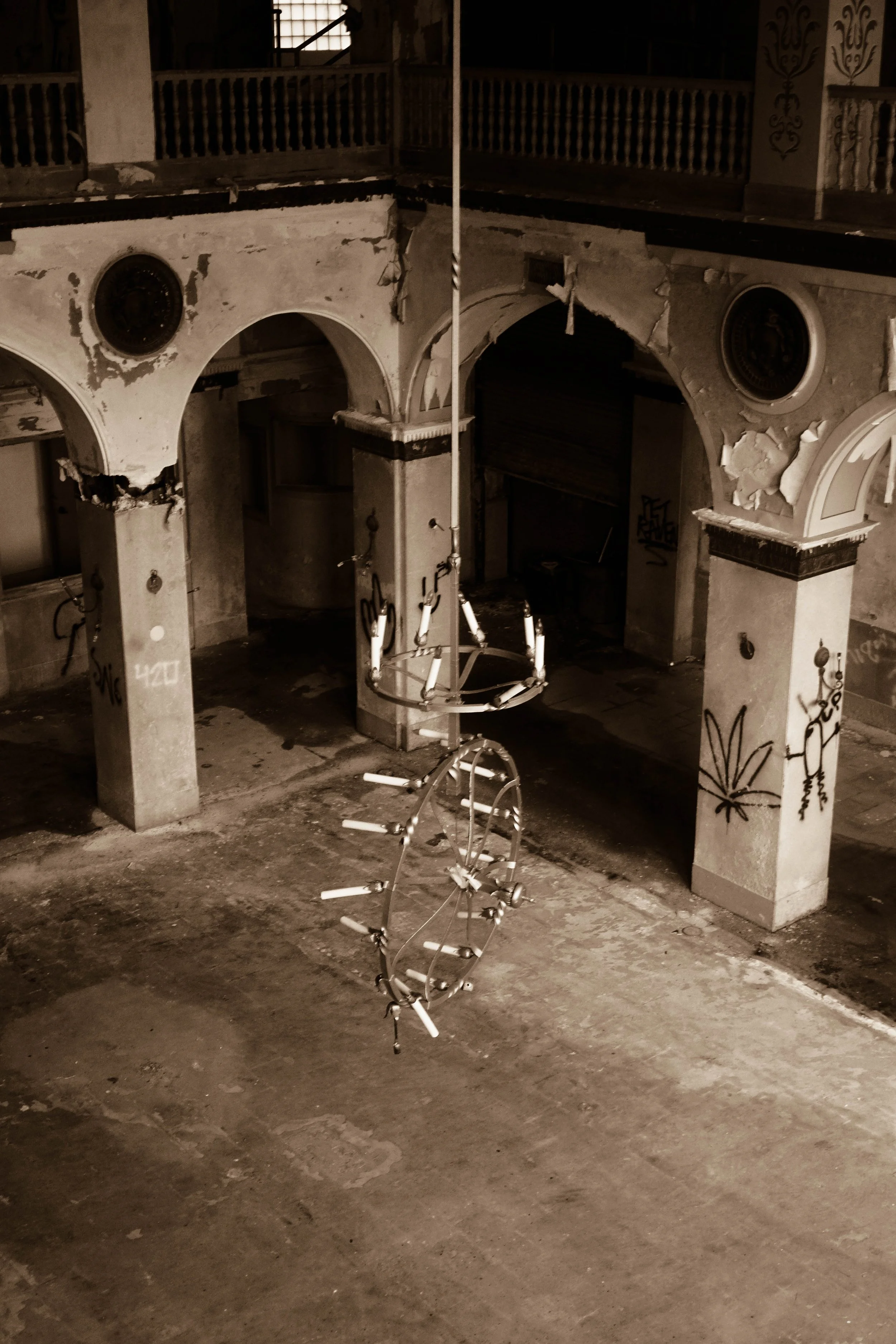 An abandoned building's interior with peeling walls, graffiti, and a hanging circular metal structure