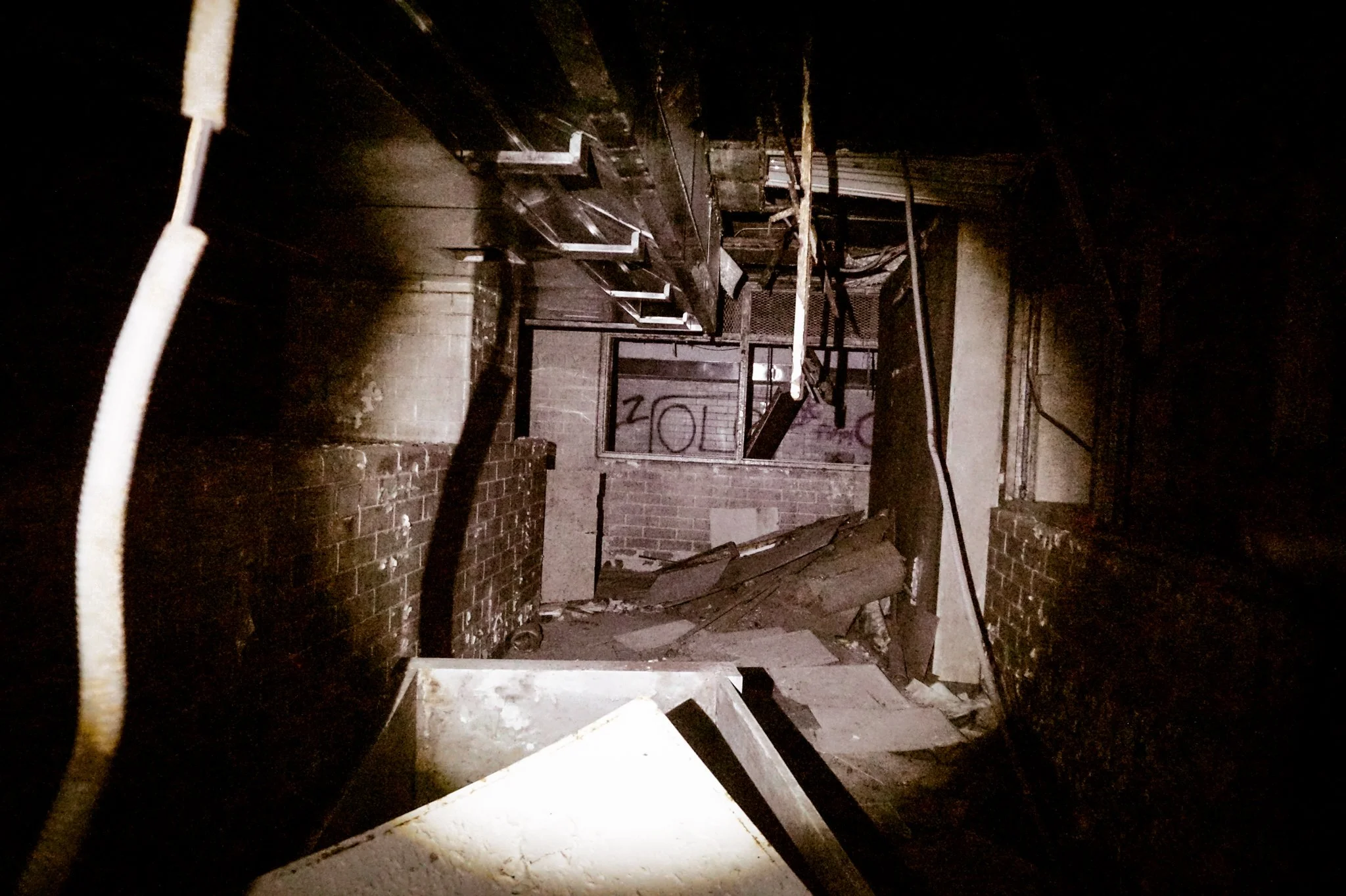 Interior of a damaged building with burned walls, debris, and charred objects.