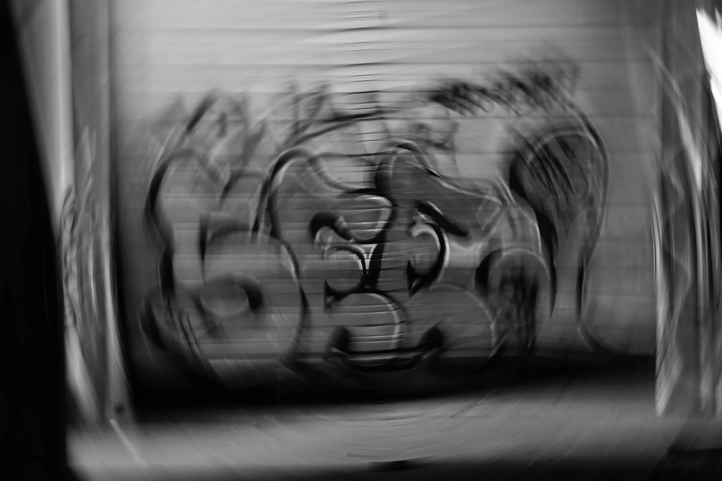 Blurred image of an intricate metal sculpture or object with curved and circular elements, possibly artwork or decorative piece.