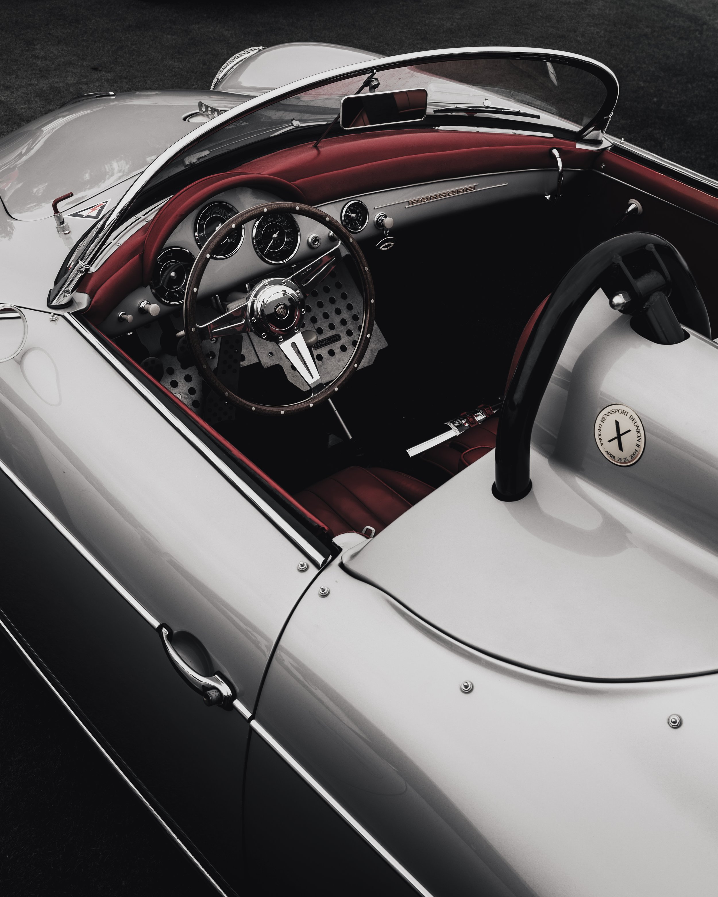Close-up of a vintage white convertible car interior with a red leather dashboard and black steering wheel.