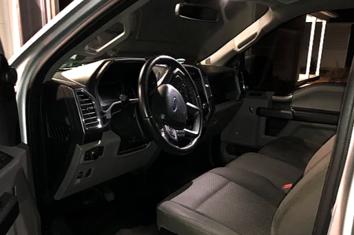 Interior of a vehicle showing the steering wheel, dashboard, and front seats.