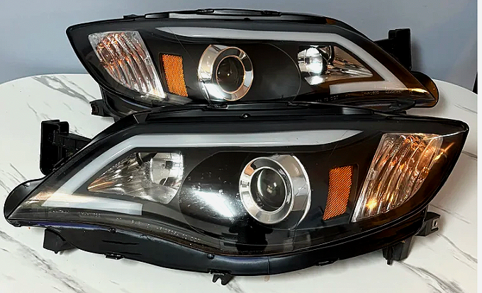 Two black car headlights with clear and amber lenses placed on a white surface.