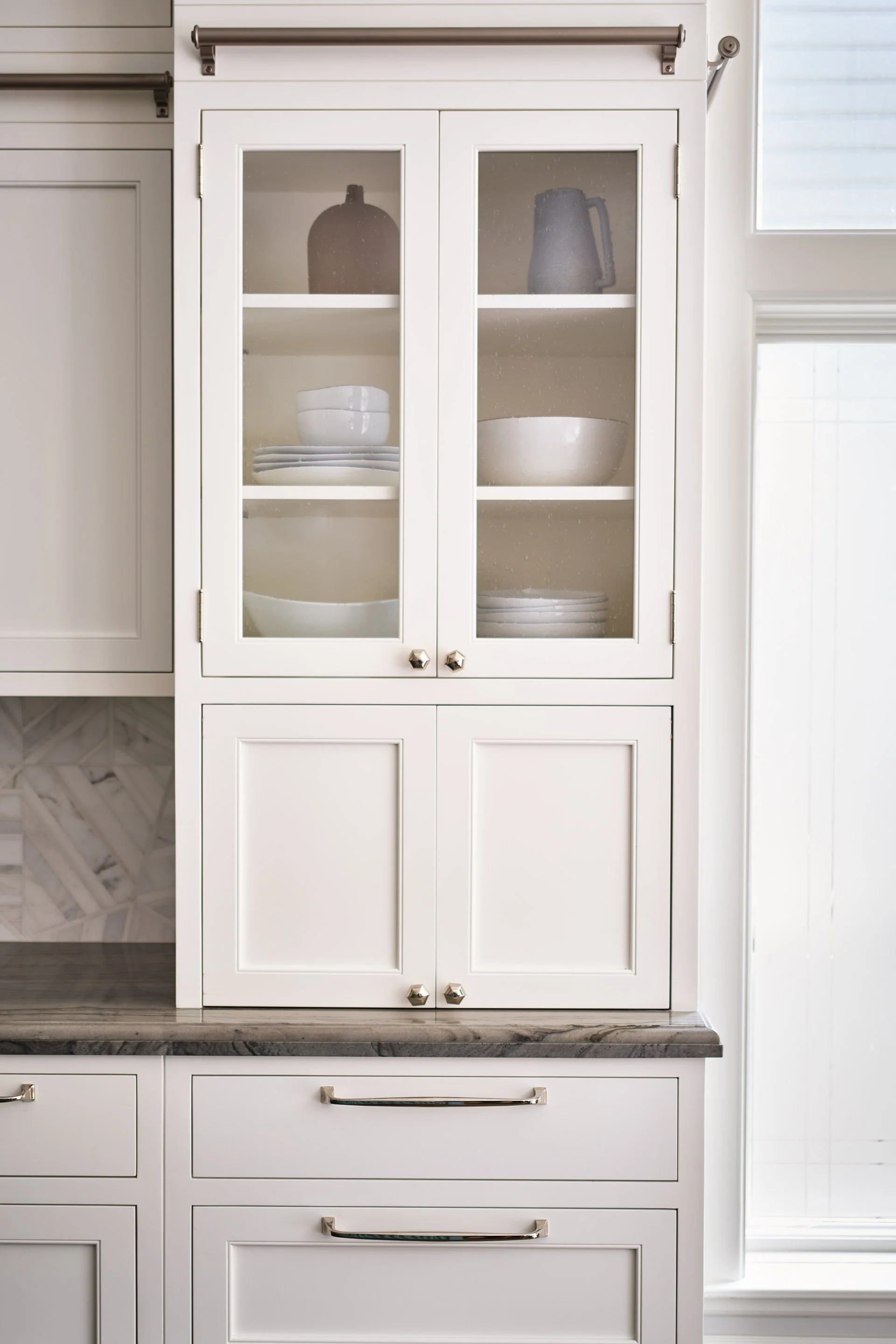 ACD | Alicia Cheung Design designed this glass-front millwork with a hidden appliance garage tucked below, pairing curated ceramics with brass hardware, creating a refined and functional storage moment.
