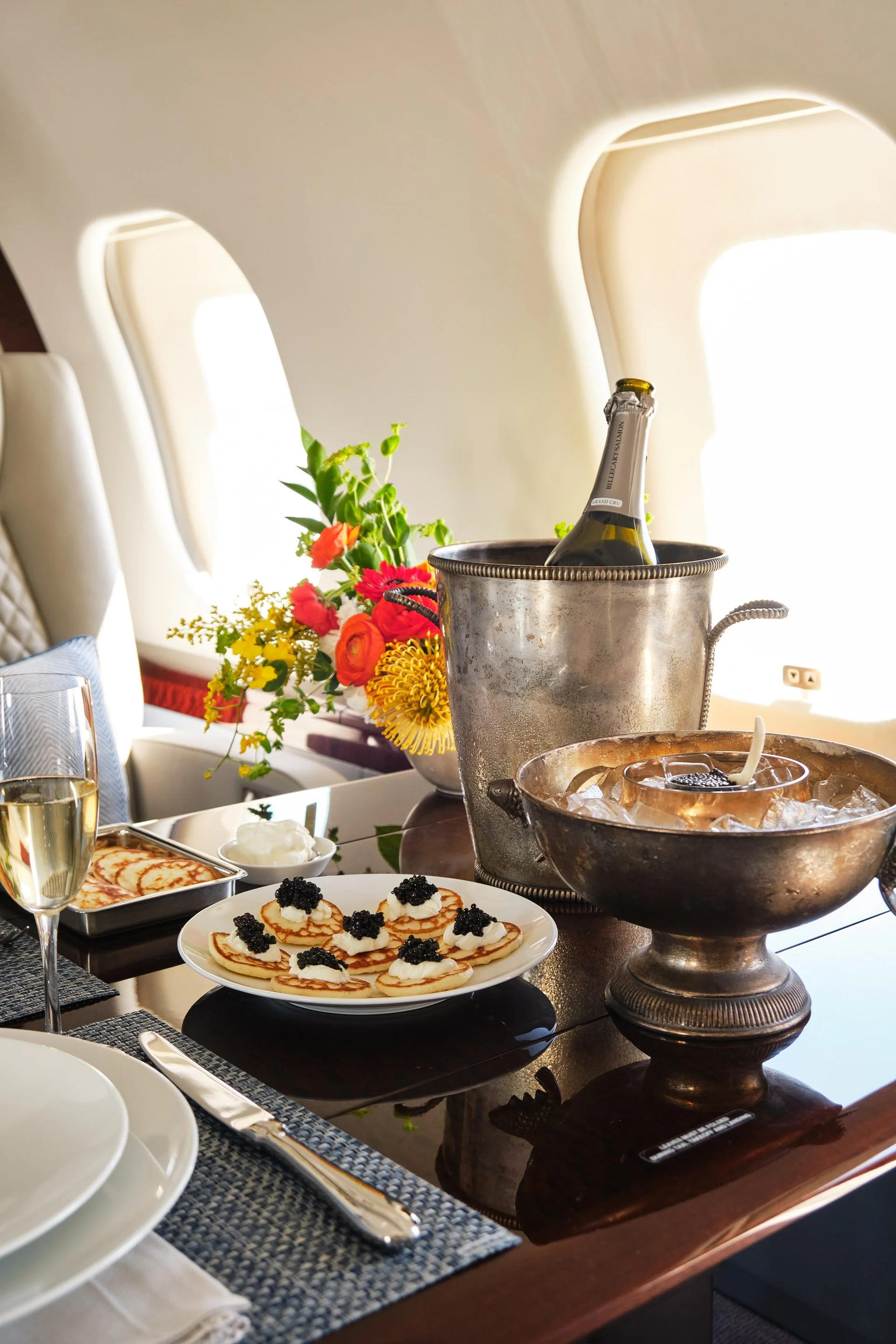 ACD | Alicia Cheung Design detailed this jet dining setup with quilted leather seating, herringbone pillows, and a formal table setting, creating an elegant and hospitable moment perfect for entertaining at altitude.