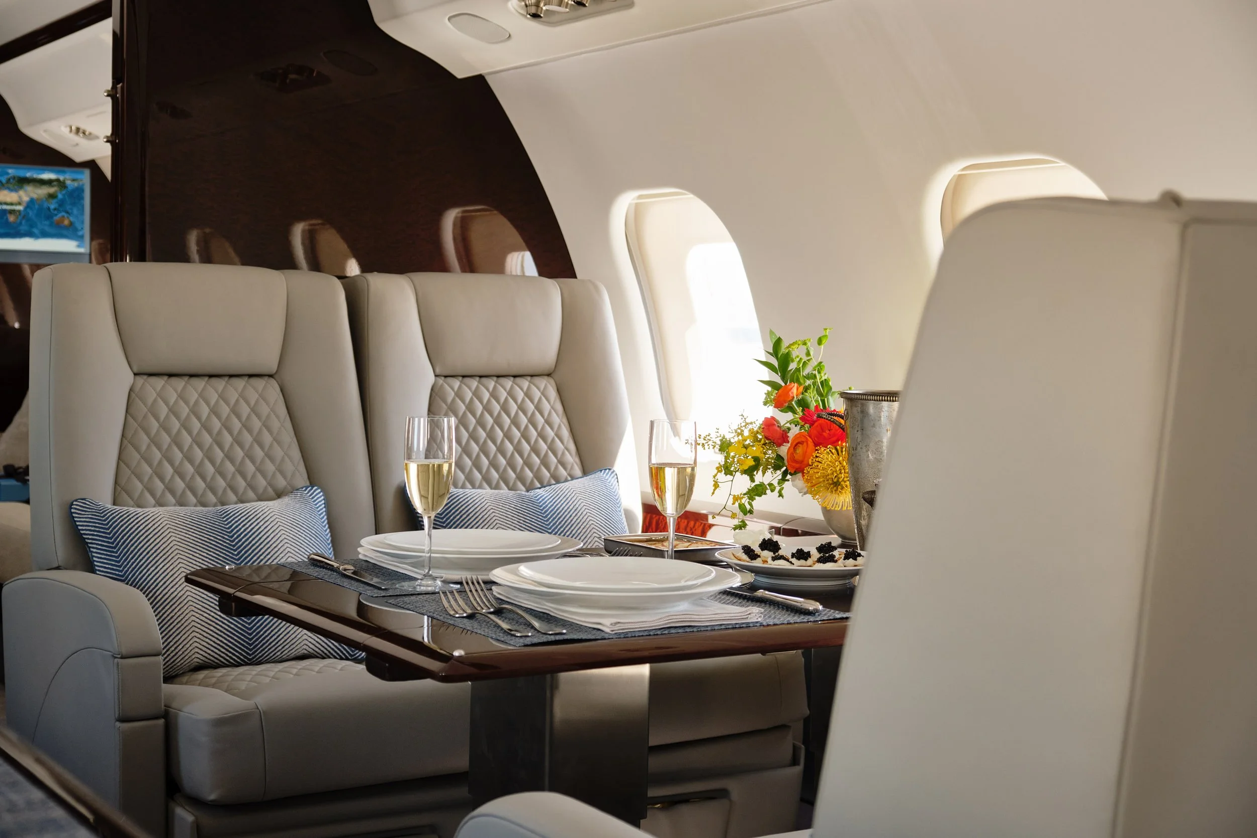 ACD | Alicia Cheung Design detailed this jet dining setup with quilted leather seating, herringbone pillows, and a formal table setting, creating an elegant and hospitable moment perfect for entertaining at altitude.