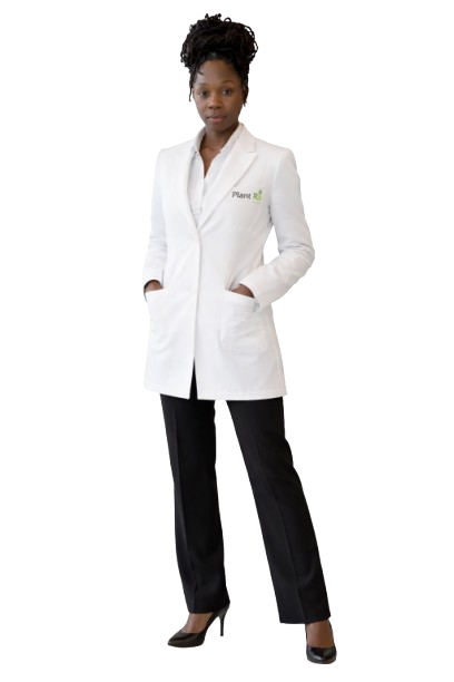 A woman standing with her hands in the pockets of her white lab coat, which has a small logo on the chest, wearing black pants and heels.