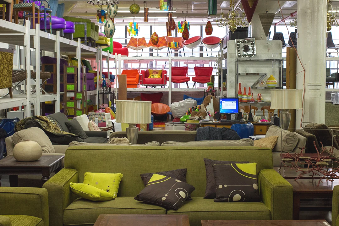 Interior of a furniture store displaying a variety of sofas, chairs, and decorative items in a spacious, industrial-style setting.