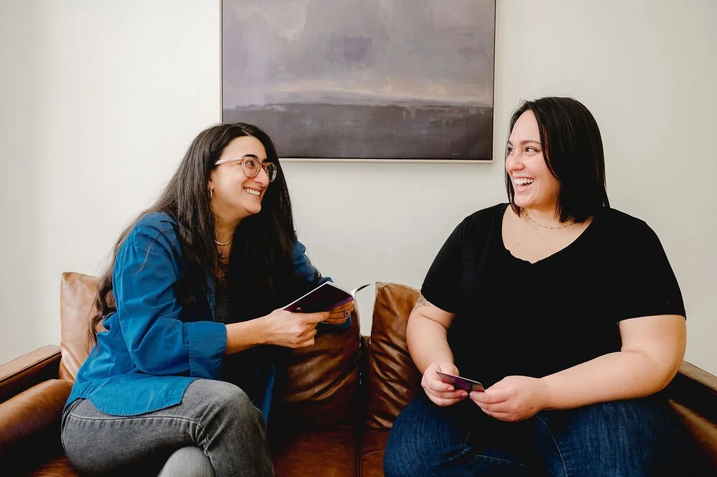 Counselor and client looking at each other and smiling while holding therapeutic cards.