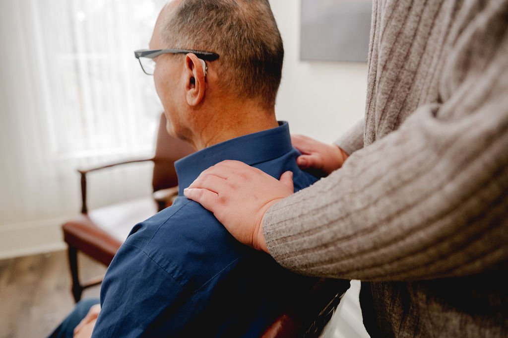 Reiki practitioner puttng her hands on clients shoulders for sitting reiki session.