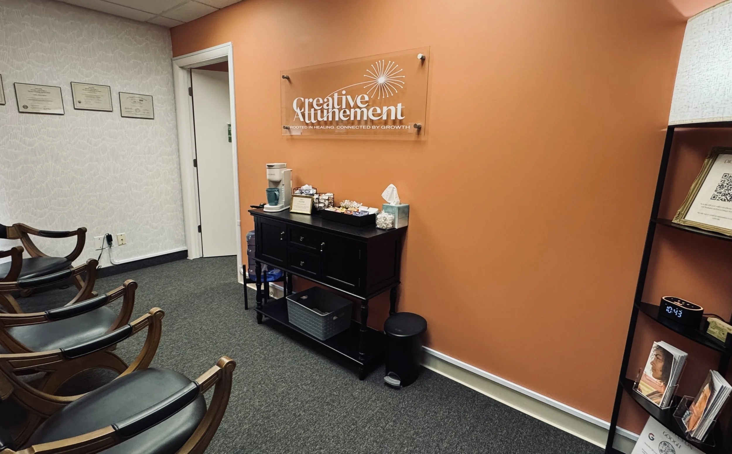 Waiting room with 3 chairs, coffee/tea bar, pamphlets and licenses on the wall.