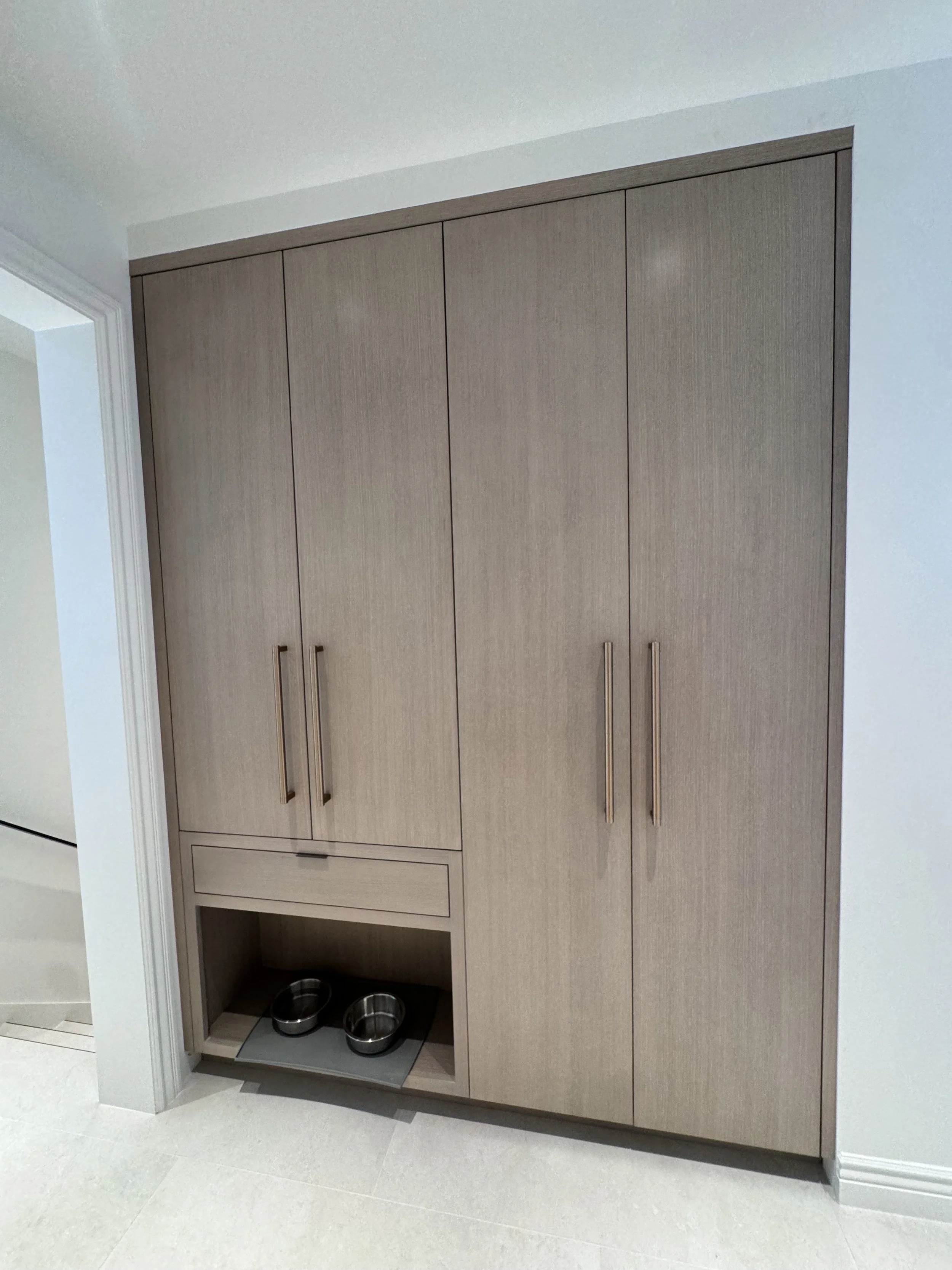 Built-in wood storage cabinets with drawers and a recessed space for pet bowls.