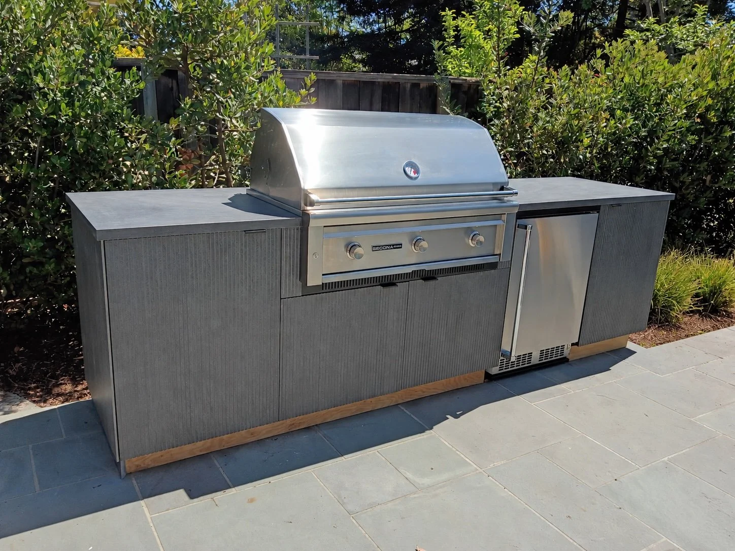 Custom outdoor kitchen with a built-in stainless steel grill, durable cabinetry, and stone countertops.