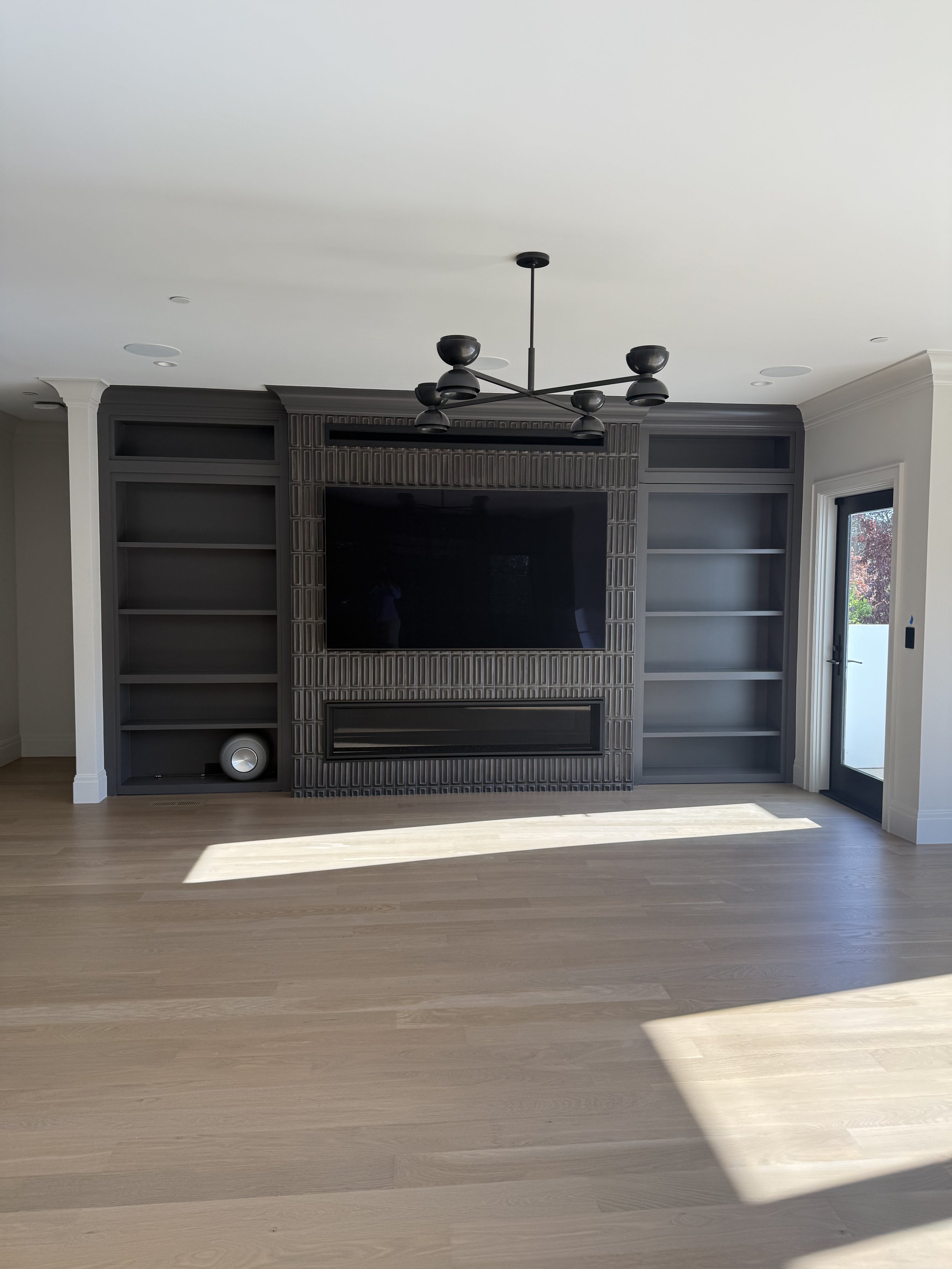 Built-in entertainment wall with dark cabinetry, open shelves, and space for a television.