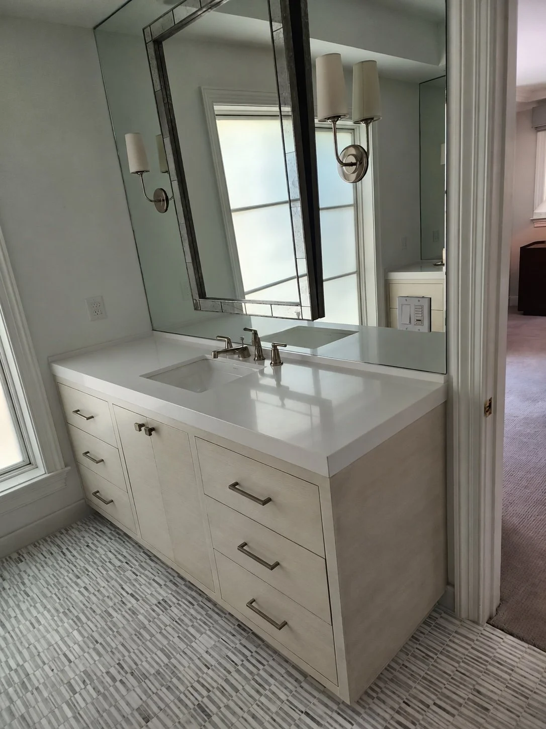Bathroom vanity with white cabinetry, a stone countertop, dual sinks, and natural light.