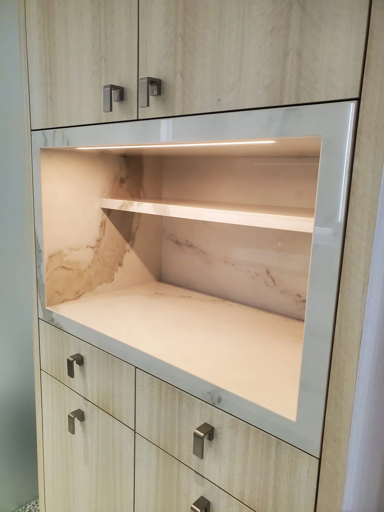 Built-in stone niche with floating shelves, accent lighting, and custom cabinetry.