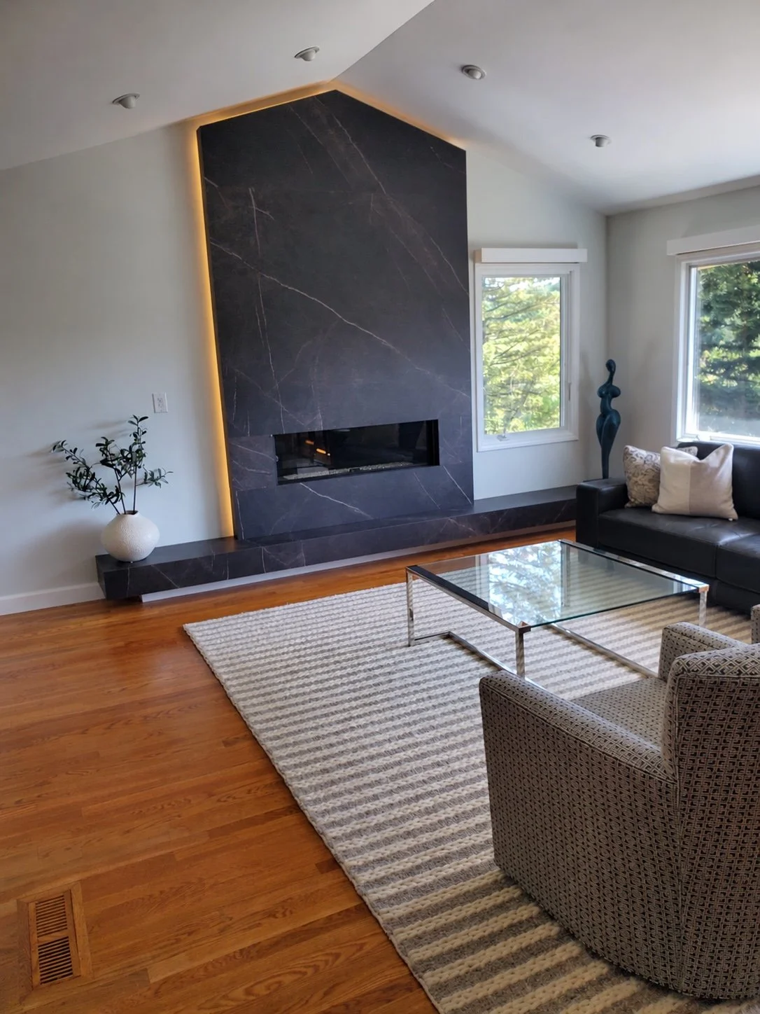 Modern fireplace feature wall with dark stone panels, warm accent lighting, and a clean contemporary design.
