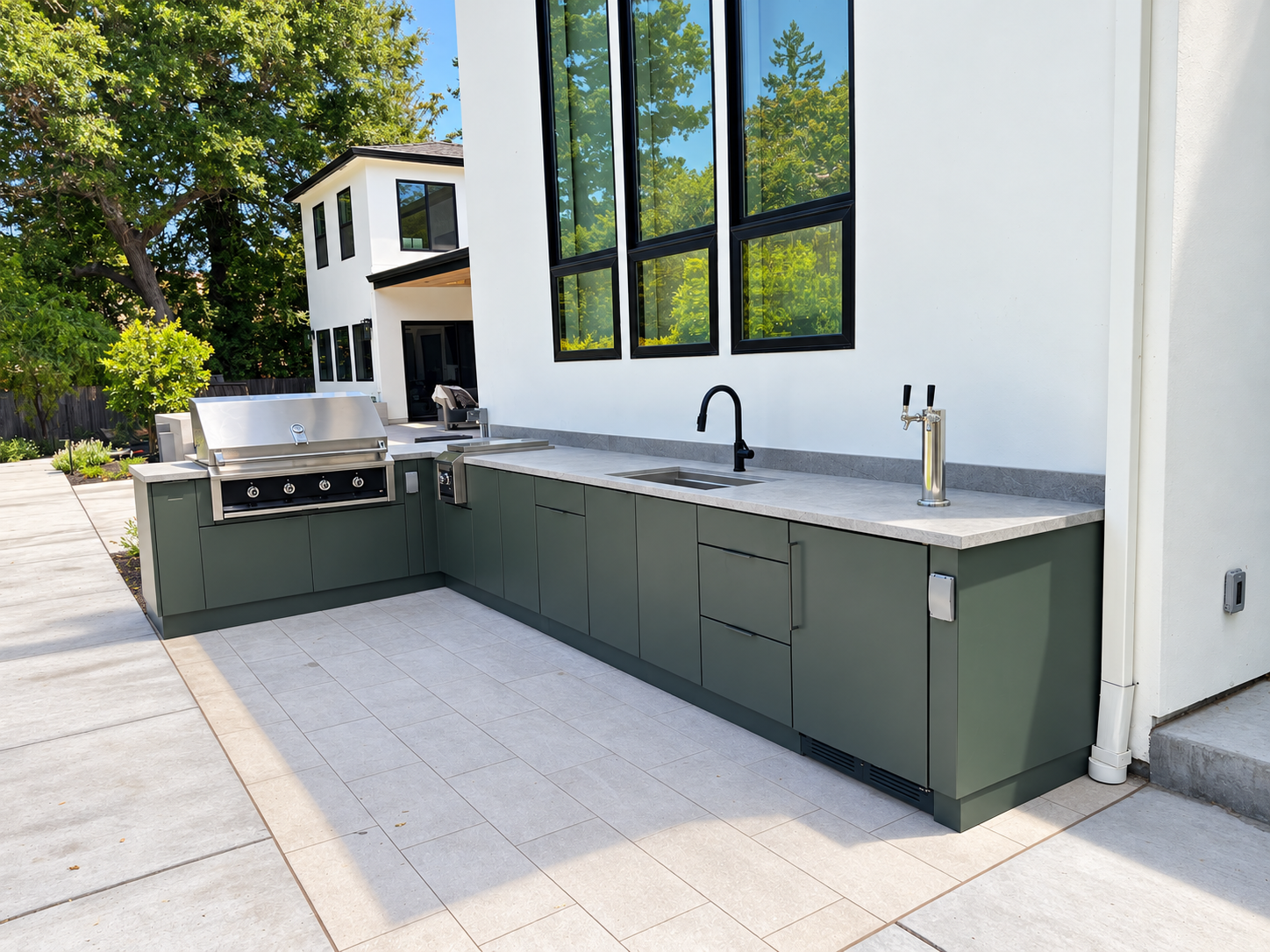 Custom outdoor kitchen with green cabinetry, a built-in stainless steel grill, sink, beverage tap, and light stone countertops.