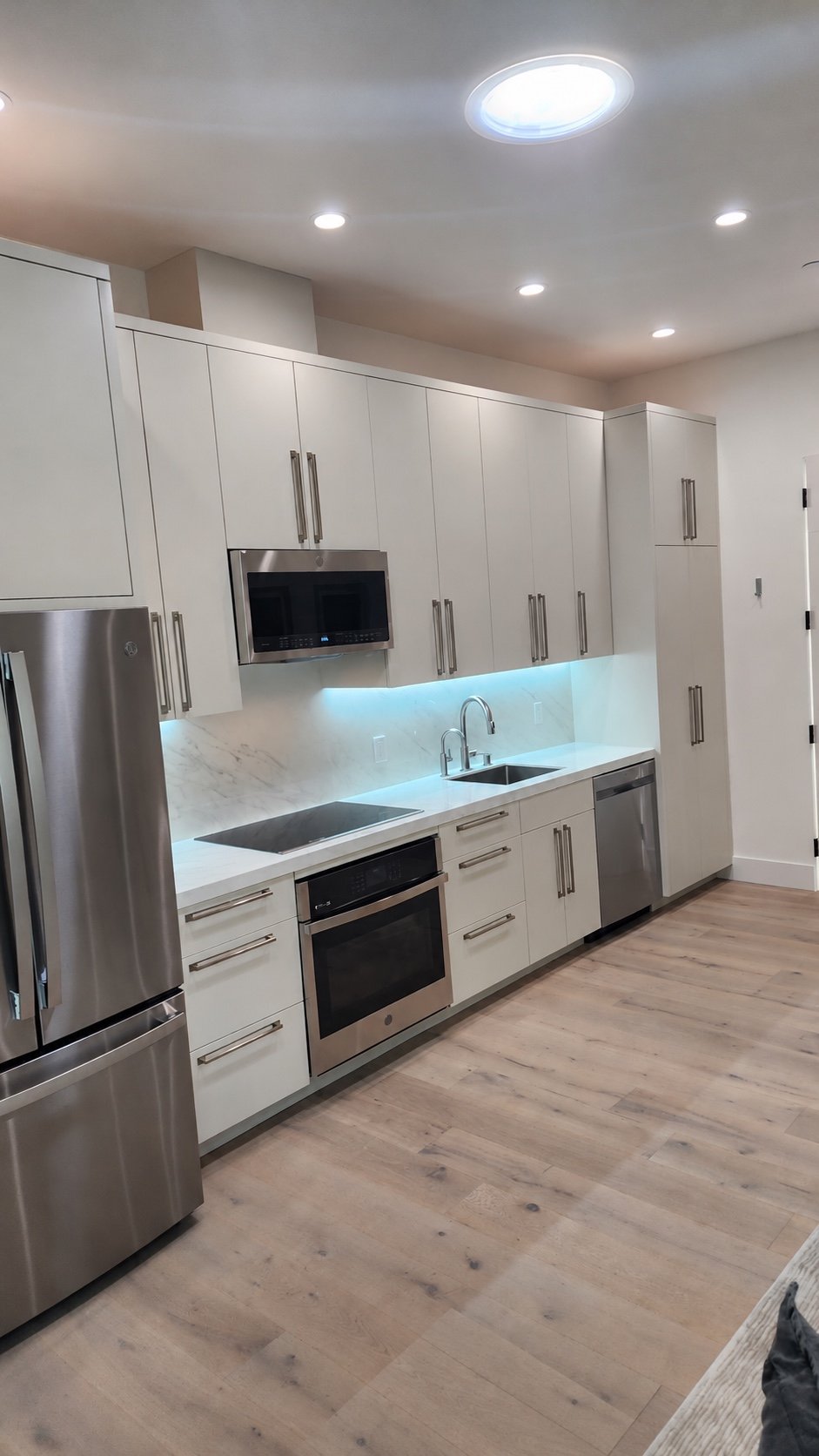 Compact modern kitchen with white cabinetry, integrated appliances, and efficient storage.