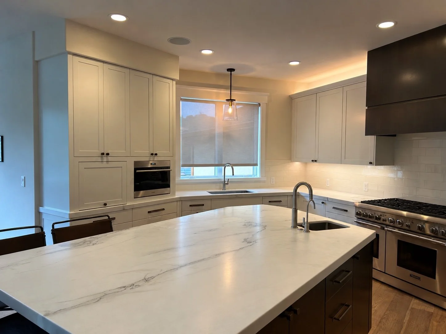 Bright remodeled kitchen with a long stone island, custom cabinetry, and modern lighting.