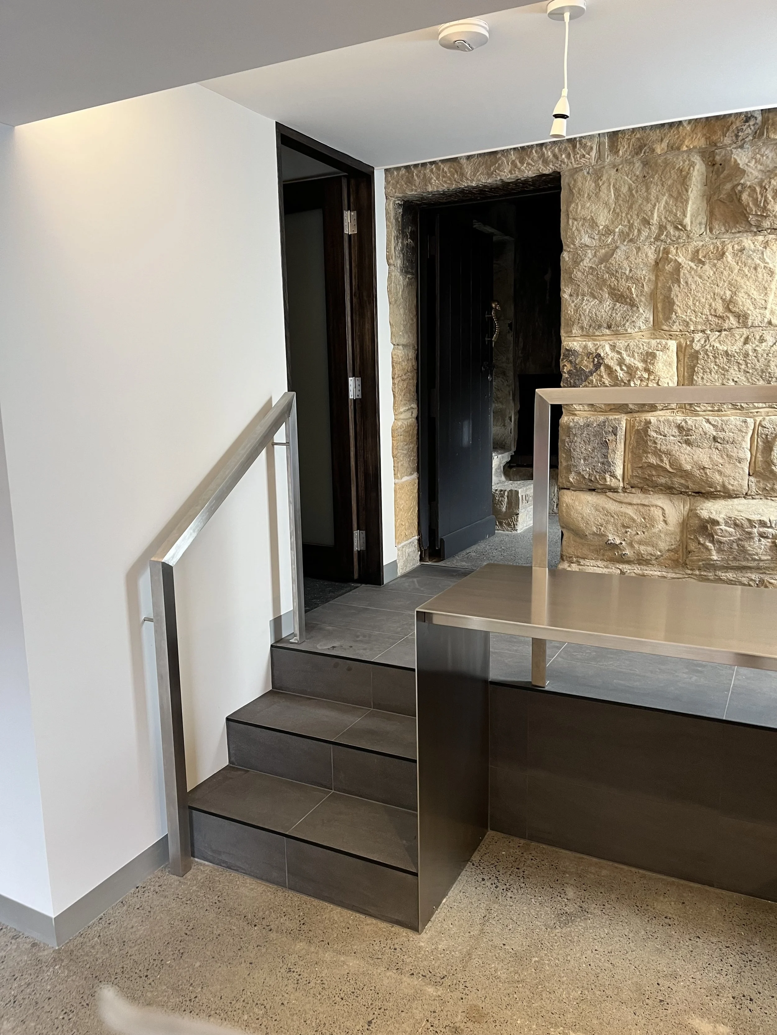 5mm stainless steel plate benchtops with a waterfall end, featuring a brushed satin  finish, in a laundry/kitchenette installed at a private residence at North Hobart.