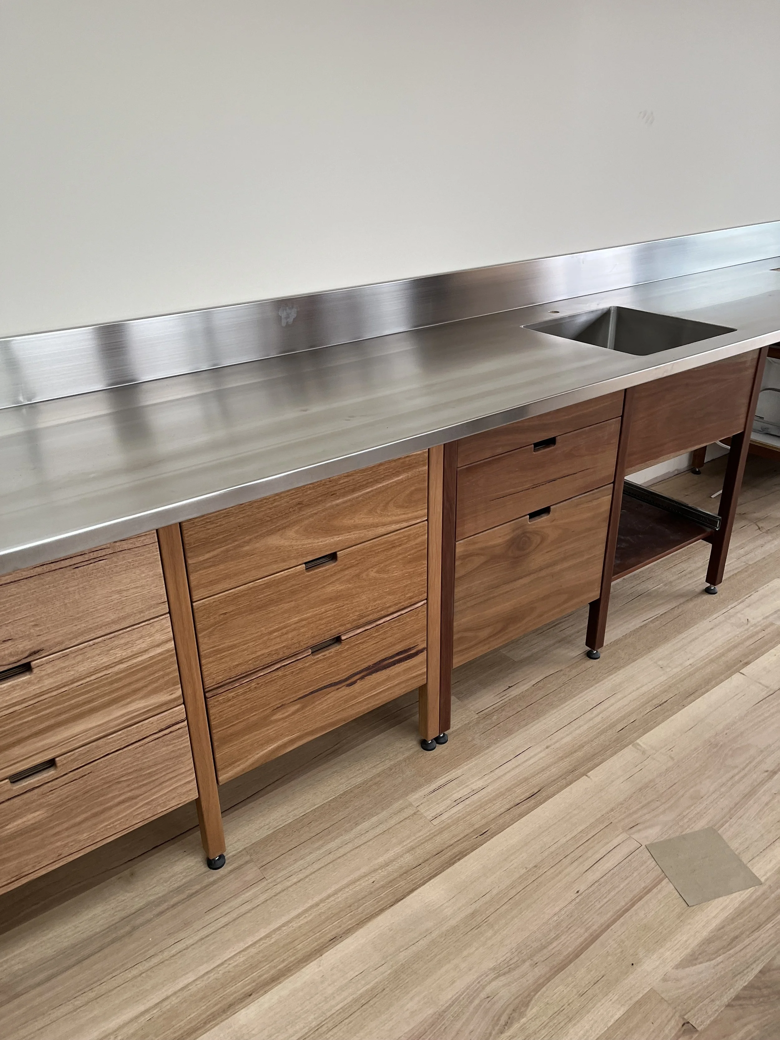 Brushed satin stainless steel bench with  integrated sink and splashback  at a private residence in Hobart.