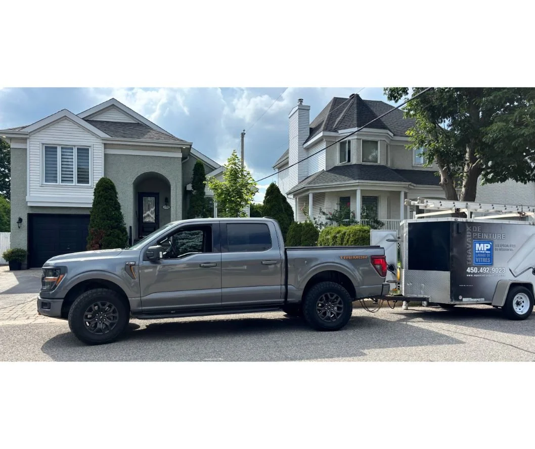 Camion et remorque lettrée de MP Entretien Peinture stationnés devant une maison à Terrebonne pendant les travaux de peinture intérieure
